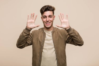 Kahverengi ceketli genç beyaz adam on numarayı elleriyle gösteriyor..