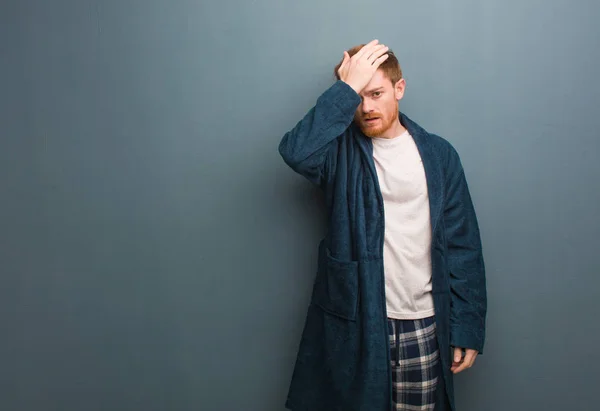 Young redhead man in pajama worried and overwhelmed