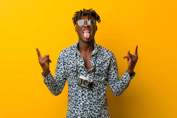 Young black rasta man wearing a vacation look showing rock gesture with fingers