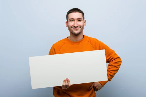 Giovane Uomo Caucasico Che Tiene Cartello Sorridente Fiducioso Con Braccia — Foto Stock