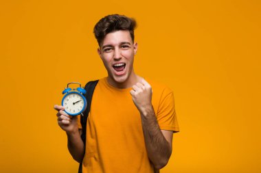 Genç bir öğrenci, elinde çalar saatle zaferi ya da başarıyı kutluyor.