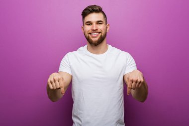 Genç yakışıklı beyaz adam parmakları ile aşağı işaret, olumlu duygu.