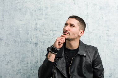 Genç rockçı şüpheli ve şüpheci bir ifadeyle yana bakıyor..