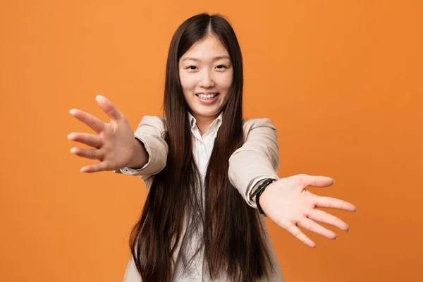 Young business chinese woman feels confident giving a hug to the camera.
