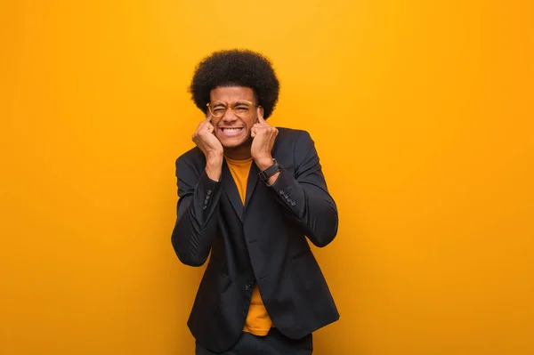 若いビジネスアフリカ系アメリカ人男性オレンジ壁の上に手で耳を覆う — ストック写真