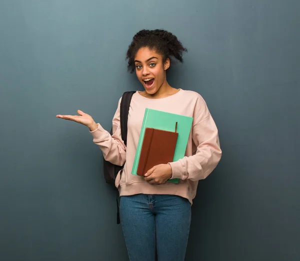 Young student black woman holding something with hand. She is holding books.