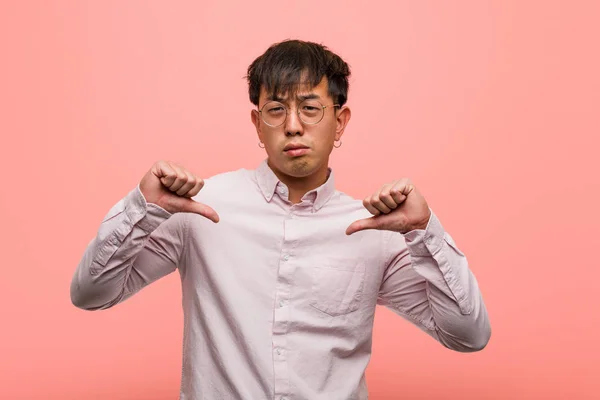 Young chinese man pointing fingers, example to follow
