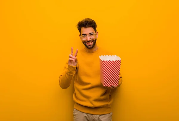 Young Man Holding Popcorns Showing Number Two — Stock Photo, Image