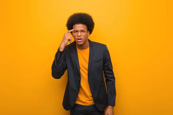 若いビジネスアフリカ系アメリカ人男性オレンジの壁に指で失望ジェスチャーを行う — ストック写真