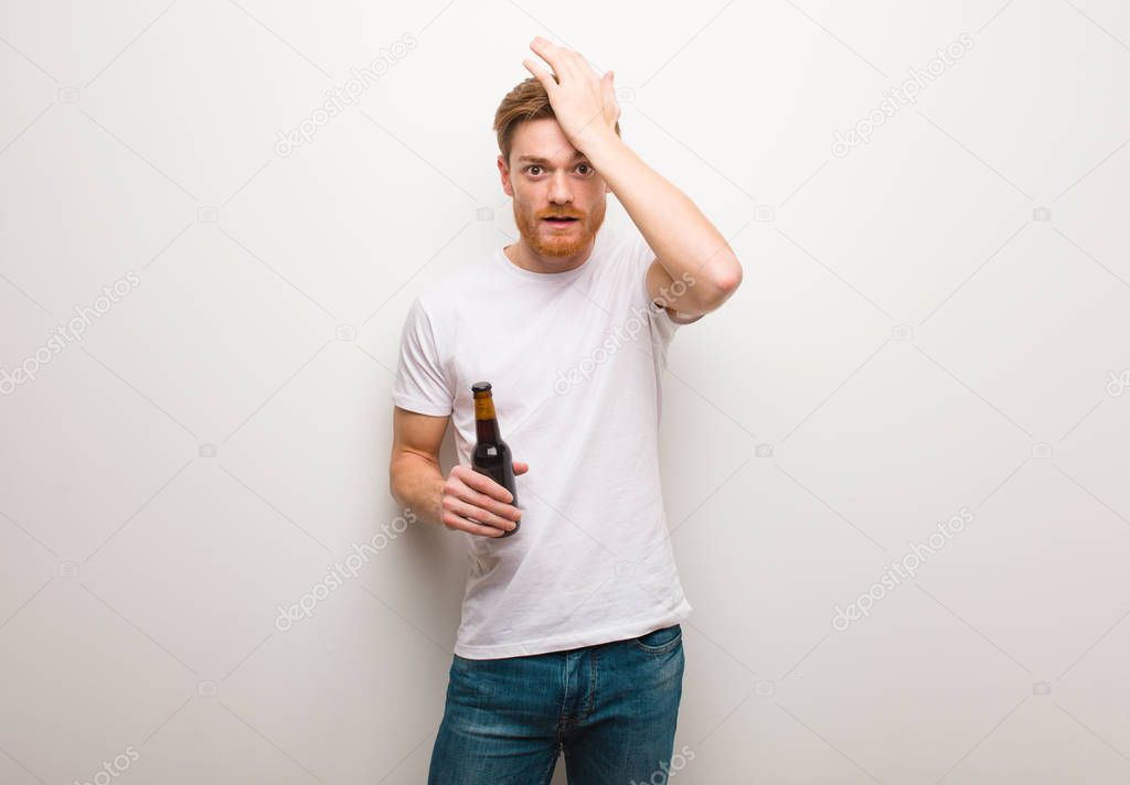 Young redhead man worried and overwhelmed. Holding a beer.