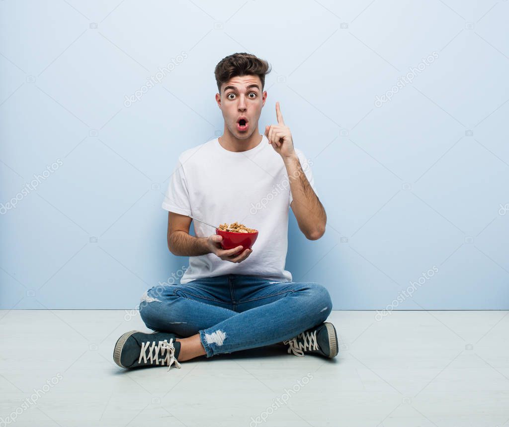 Young man eating cereals sitting on the floor having some great idea, concept of creativity.