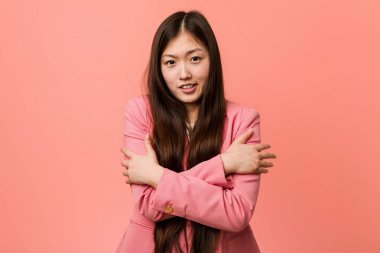 Pembe takım elbiseli genç Çinli kadın düşük ateş ya da hastalık yüzünden soğuyor..