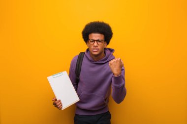 Genç Afro-Amerikan öğrenci elinde bir not panosuyla yumruk yumruğa, kızgın bir ifadeyle