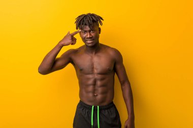 Genç siyah adam mayo giyiyor ve işaret parmağıyla hayal kırıklığı işareti yapıyor..