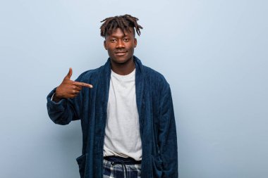 Genç Afrikalı, pijamalı bir adam gömleğin fotokopi odasını gösteriyor, gururlu ve kendinden emin.