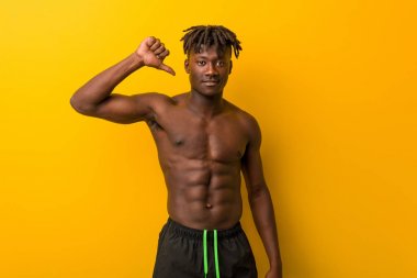 Genç siyahi adam mayo giyiyordu. Hoşlanmadığı bir hareket gösteriyordu. Başparmakları aşağıda. Anlaşmazlık konsepti.