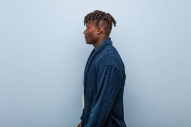 Genç Afrikalı siyah adam pijama giymiş, sola bakıyor, yandan bakıyor..