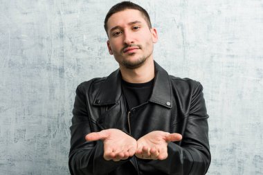 Genç rockçı elinde avuç içi bir şeyle kameraya sunuyor..