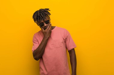 Güneş gözlüğü takan genç siyahi bir adam ağzını eliyle kapatan bir fotokopi odasına dikkatlice bakıyor..