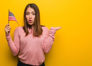 Amerika Birleşik Devletleri bayrağını tutan genç ve güzel bir kadın avucunda bir şey tutuyor.