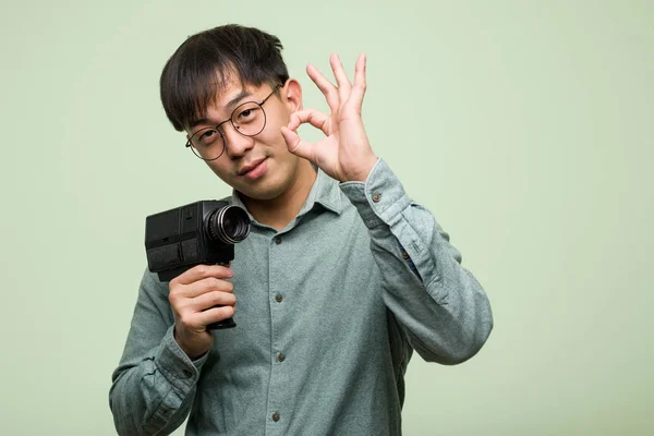 若いです中国人男保持していますヴィンテージカメラ陽気で自信を持っていますOkジェスチャー — ストック写真