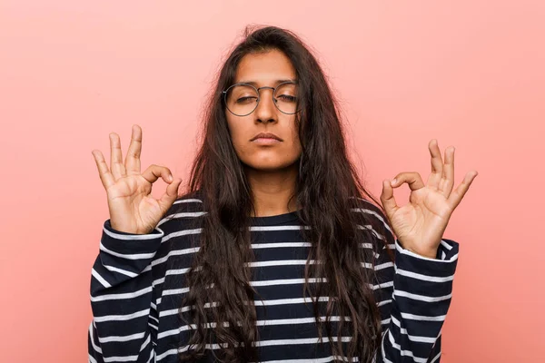 Young intellectual indian woman relaxes after hard working day, he is performing yoga.