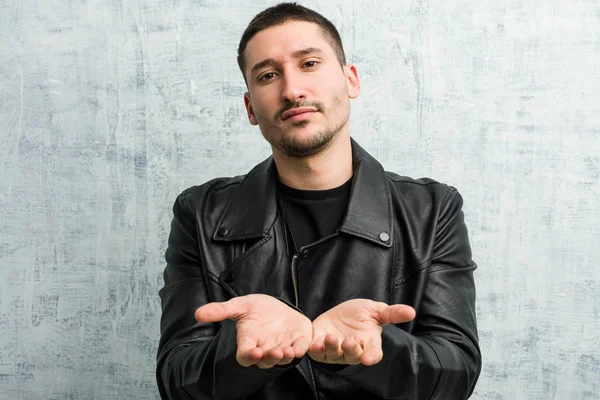 Genç rockçı elinde avuç içi bir şeyle kameraya sunuyor..