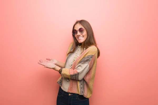 Young hippie woman on pink background holding something with hands