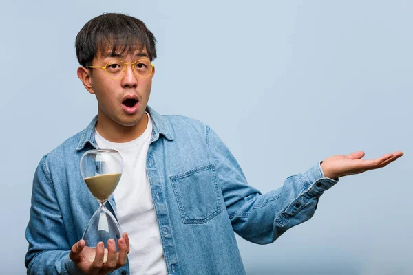 Junger Chinese Mit Sanduhr Der Etwas Auf Der Hand Hält — Stockfoto