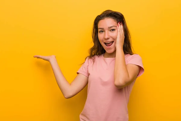 Young European Woman Isolated Yellow Background Holds Copy Space Palm — 스톡 사진