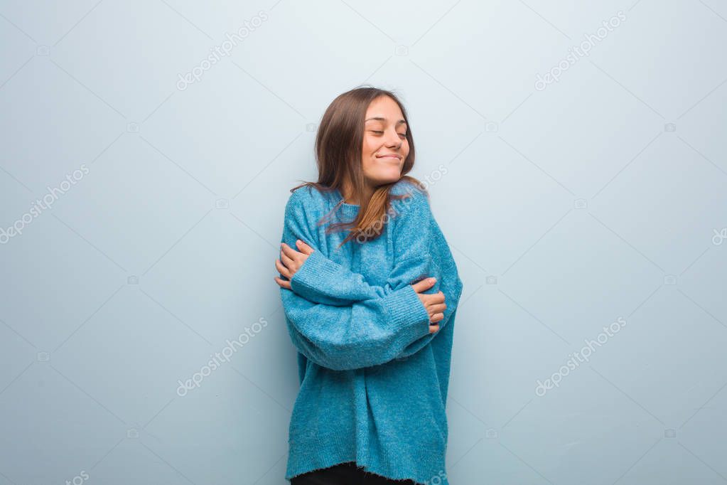 Young pretty woman wearing a blue sweater giving a hug