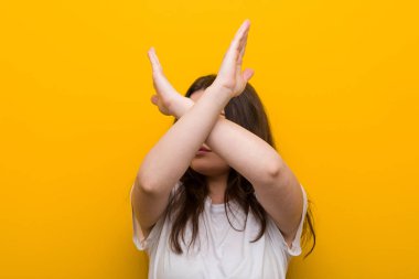 Genç, kıvrımlı, kilolu bir kadın iki kolu çapraz tutuyor, inkar kavramı.