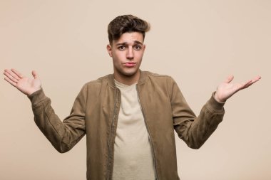 Kahverengi ceketli, genç, beyaz bir adam sorgulama sırasında omuzlarını silkiyor..