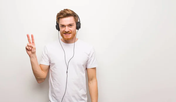 Joven Pelirrojo Mostrando Número Dos Escuchar Música Con Auriculares — Foto de Stock