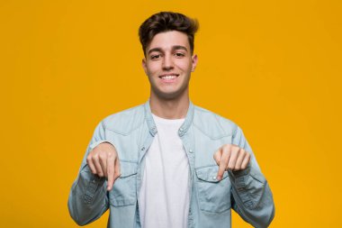 Kot gömlek giyen genç yakışıklı öğrenci parmaklarıyla işaret ediyor, pozitif duygu..