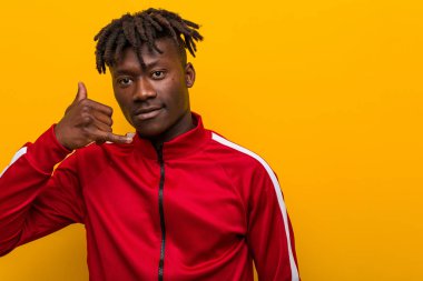 Genç fitness zencisi parmaklarıyla bir cep telefonu hareketi gösteriyor..