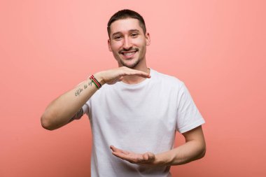 Genç adam iki eliyle bir şey tutuyor, ürün sunumu..