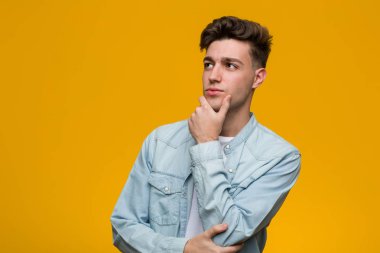 Kot gömlek giyen genç yakışıklı bir öğrenci şüpheli ve şüpheci bir ifadeyle yana bakıyor..