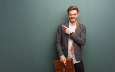 Genç kızıl saçlı iş adamı parmağıyla kenarı işaret ediyor.