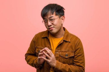 Ceket giyen genç Çinli bir adam plan yapıyor.