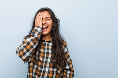 Genç havalı Hintli kadın yüzünün yarısını avuç içiyle örterek eğleniyor..