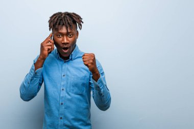 Genç Rasta 'nın elinde bir telefon tutan, tasasız ve heyecanlı genç bir zenci. Zafer konsepti.