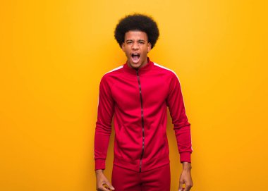 Turuncu bir duvarın üzerinden bağıran genç bir zenci. Çok sinirli ve saldırgan.