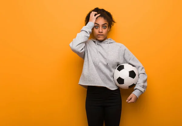 年轻健康的黑人妇女忧心忡忡 不知所措 拿着足球 — 图库照片