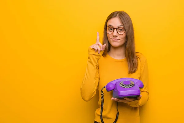 Joven Mujer Bastante Caucásica Mostrando Número Uno Ella Sostiene Teléfono —  Fotos de Stock