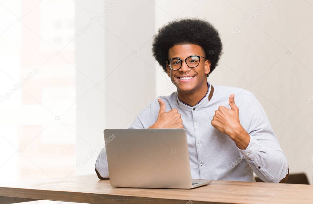 Young black man using his laptop surprised, feels successful and prosperous