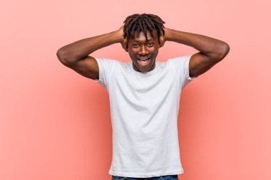 Genç Afrikalı siyahi adam ellerini başının üstünde tutarak neşeyle gülüyor. Mutluluk kavramı.