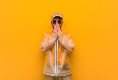 Yağmurluk giyen genç adam çok korkmuş ve saklanmış.