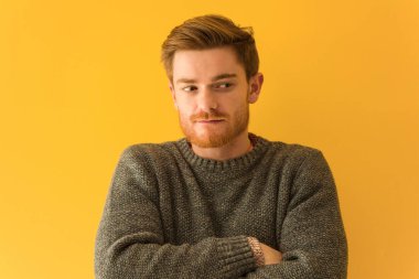 Genç kızıl saçlı adamın yüzü, kendine güvenen ve kollarını kavuşturan bir gülümseme.