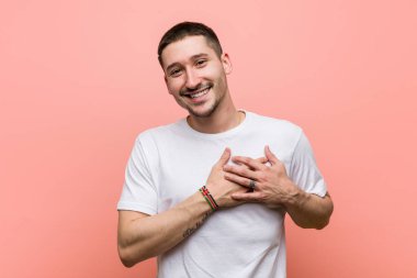 Genç adam samimi bir ifadeye sahip, avuçlarını göğsüne bastırıyor. Aşk konsepti.